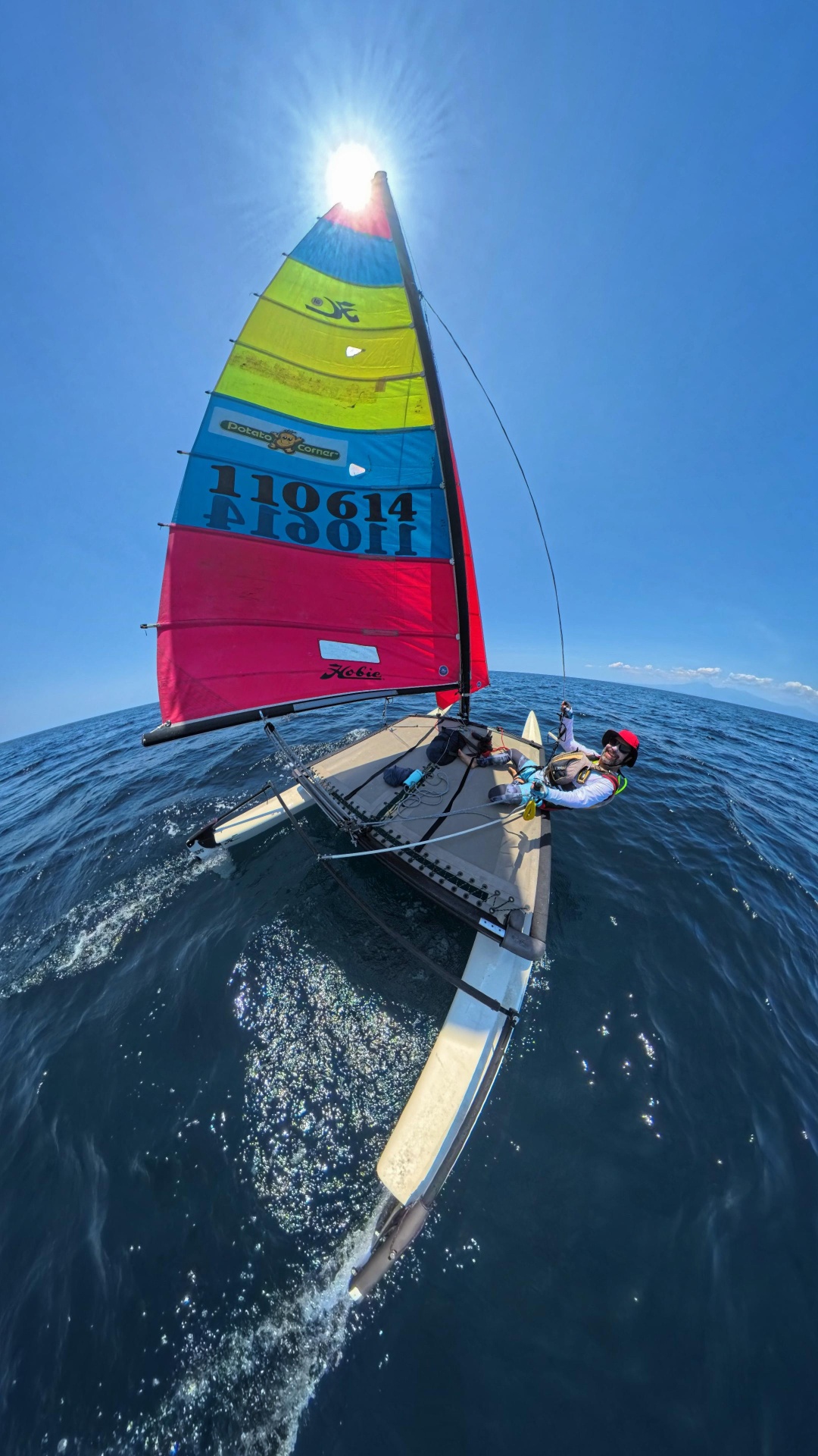 Solo at the helm — fisheye view from the trampoline at sea.
