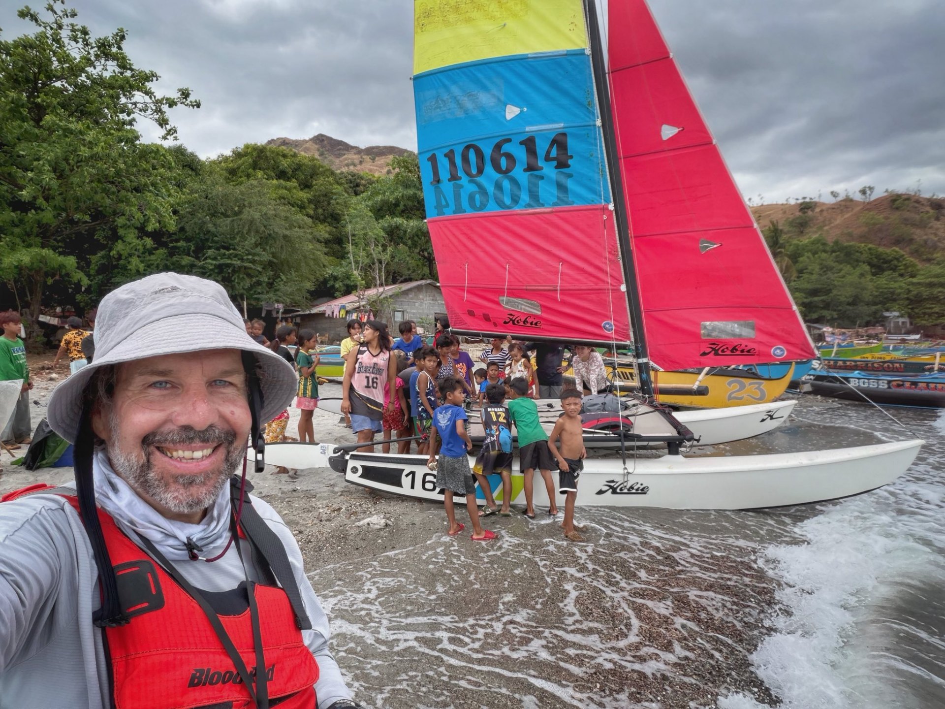 Coming ashore — community greeting on landing, sail #110614 in the surf.